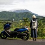 A traveller with a scooter overlooking rice fields and mountains in Bali