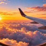 View from an airplane window above the clouds at sunrise