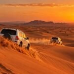 4x4 vehicles driving over red sand dunes on a desert safari near Dubai at sunset