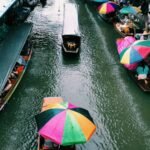 Long-tail boats and colourful umbrellas on a floating market canal near Bangkok
