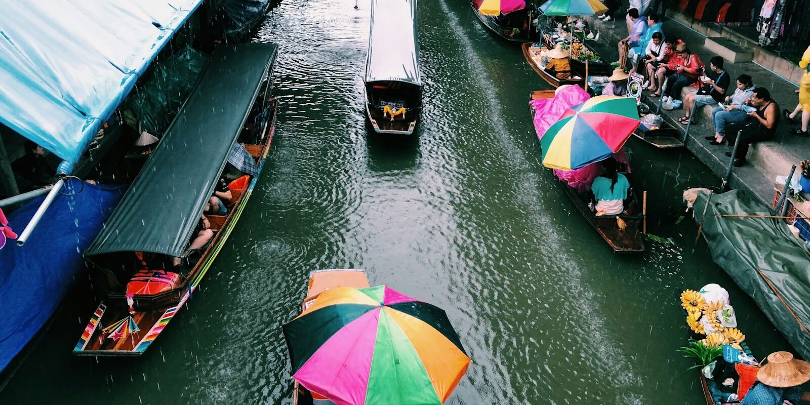 Long-tail boats and colourful umbrellas on a floating market canal near Bangkok