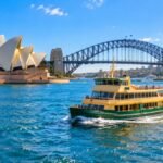 A Sydney ferry crossing the harbour with the Opera House and Harbour Bridge behind