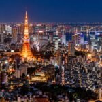 Tokyo Tower lit up at night, seen from an observation deck over the city