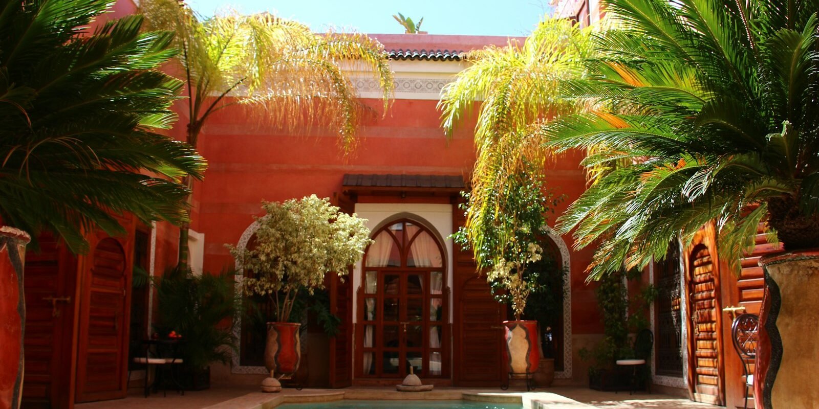 A riad courtyard with a pool and palm trees in Marrakech